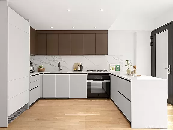 A kitchen with white cabinets and wood floors.