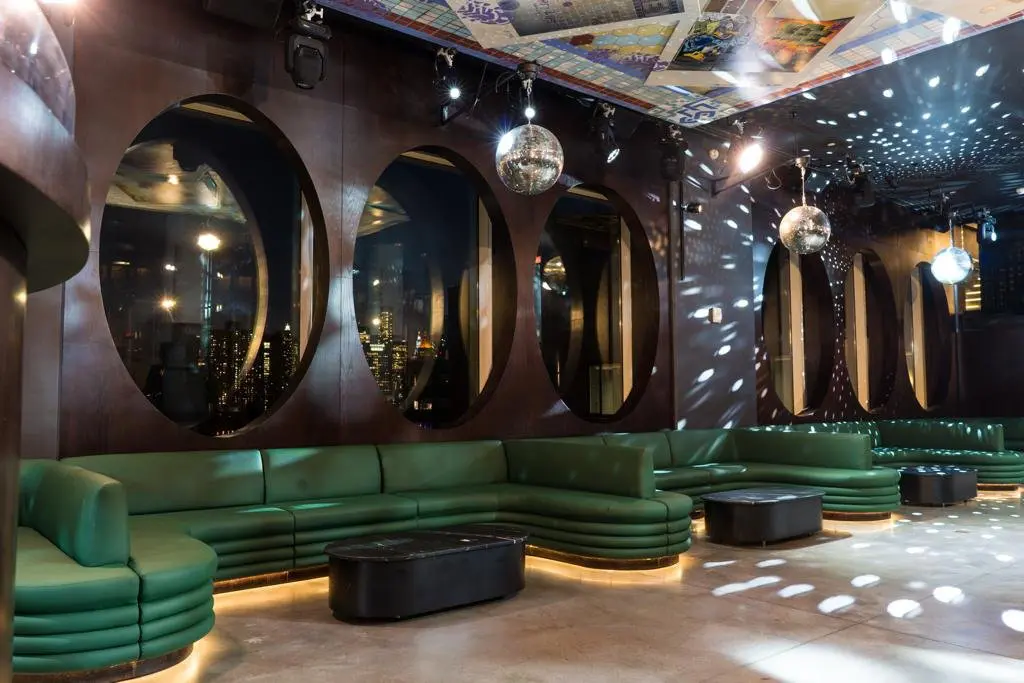 A room with green couches and mirrors on the wall.